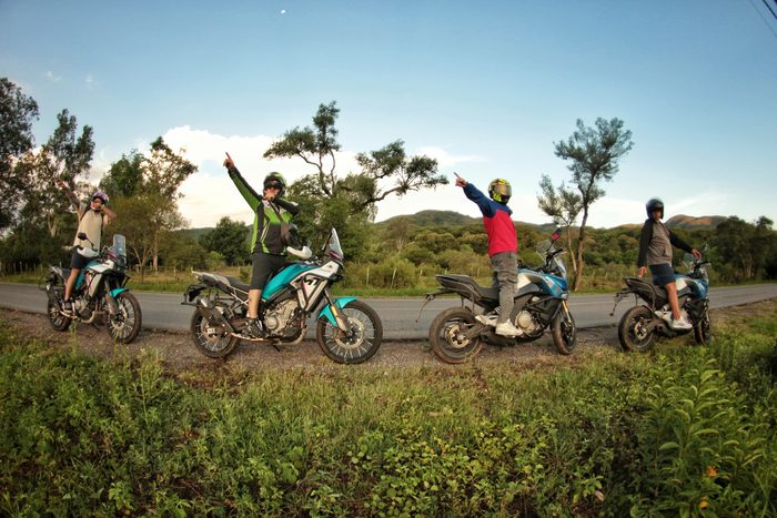Cuatro riders festejando al costado de la ruta, con las motos apoyadas